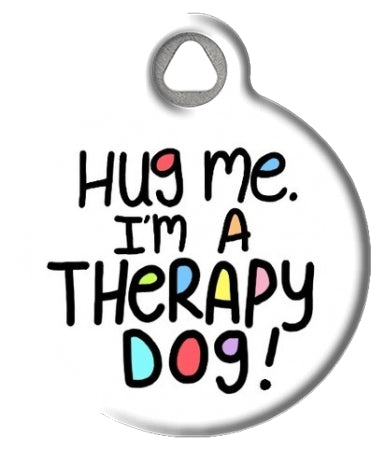 A plastic ID tag for a therapy dog with the text 'HUG ME. I'M A THERAPY DOG!' and a colorful illustration of a dog.